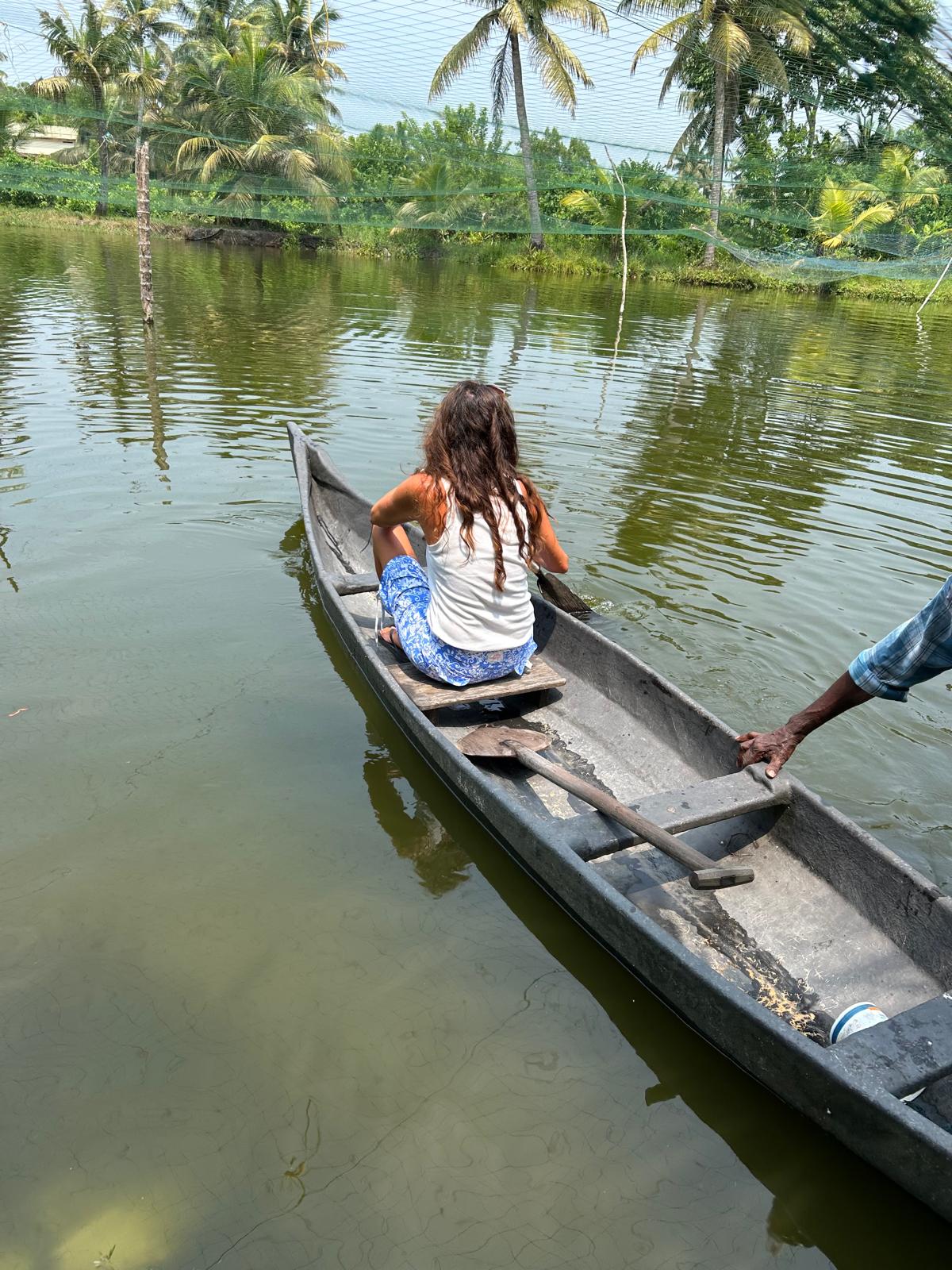Lottie paddling a wooden canoe on the backwaters