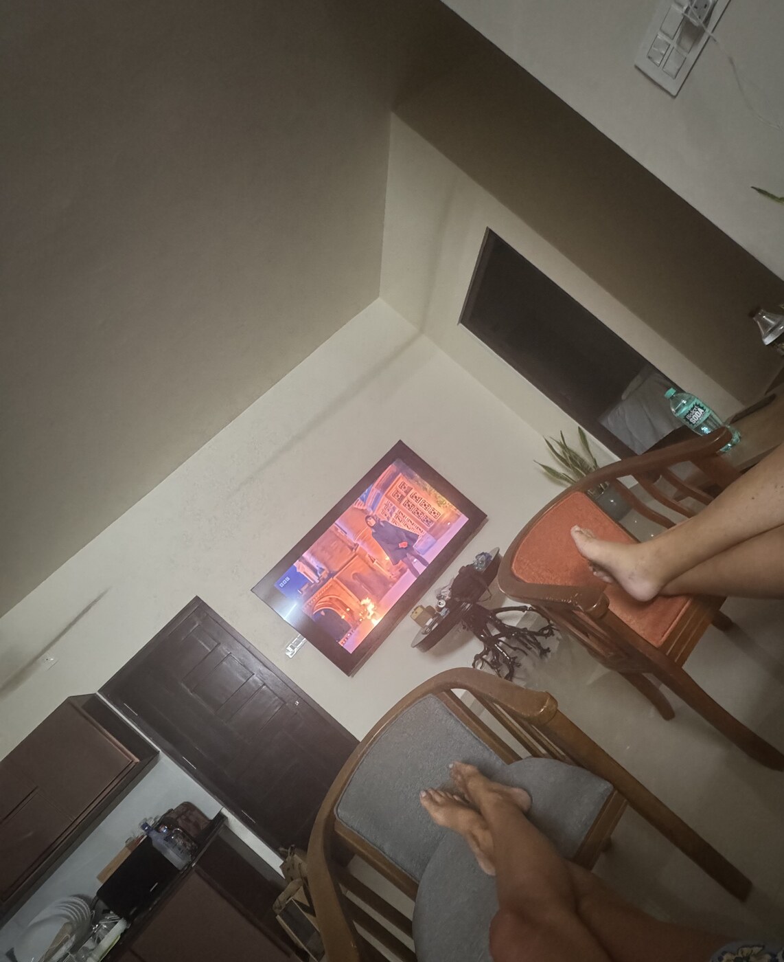 Matt and Lottie’s feet up in front of the homestay TV, showing an episode of The Traitors
