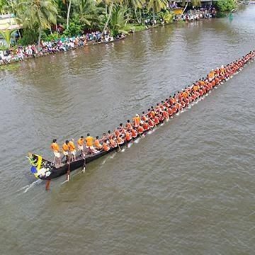 A long snake boat with a crew of paddlers on the water