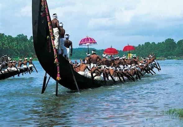Raised snake-boat prow, paddlers and colourful parasols