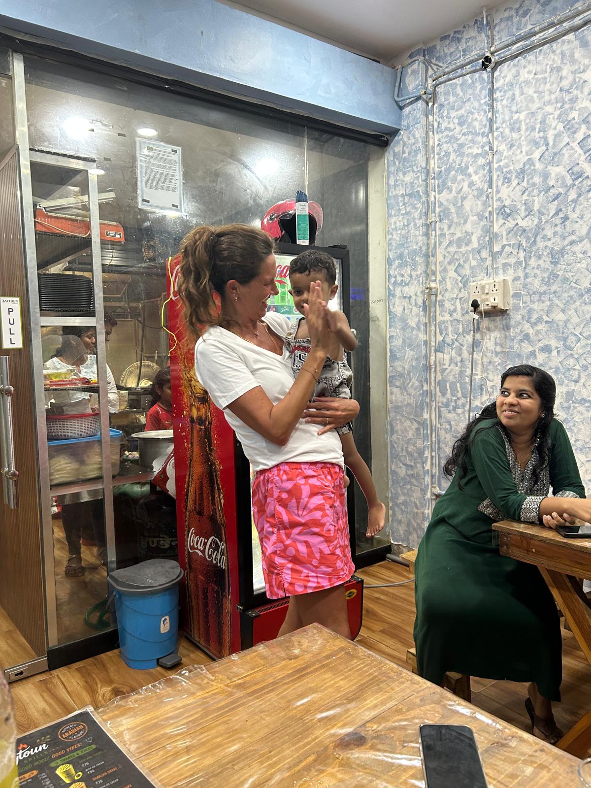 Lottie sharing a high five with a small boy in a local café