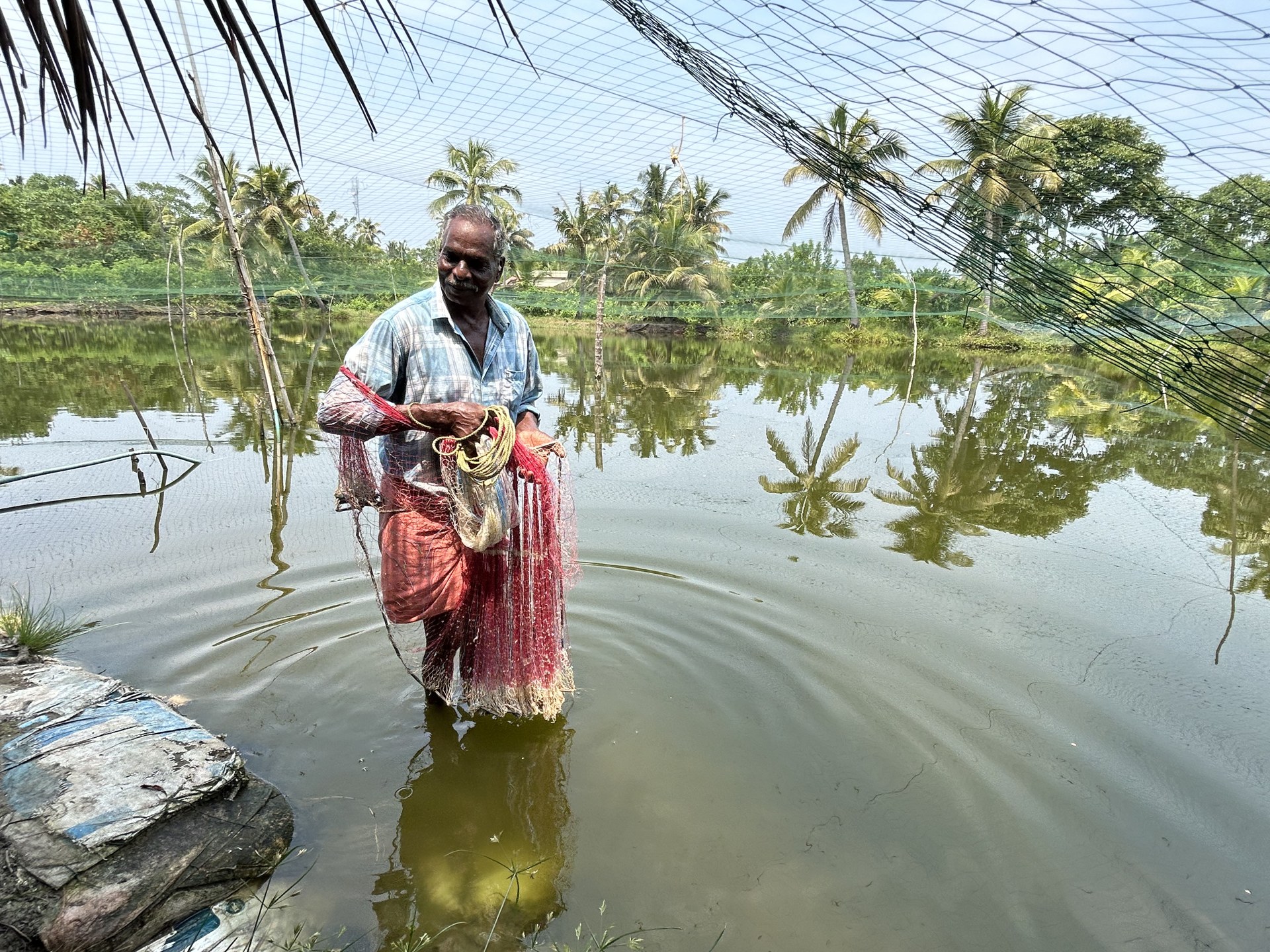 Our fish-farmer host standing in the water holding his fishing net
